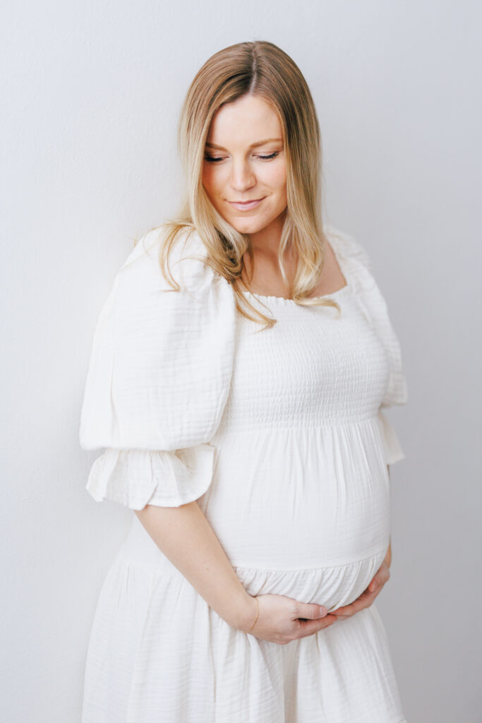 maternity photo shoot with white dress and white backdrop