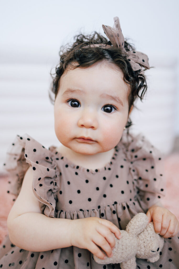 six month old wearing polka dot dress and taupe hairbow from columbus babysitters