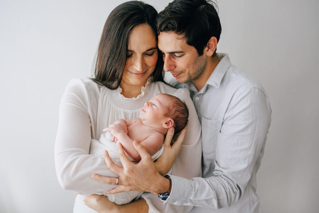 family photograph of newborn son. Mother holding baby father hugging from the side