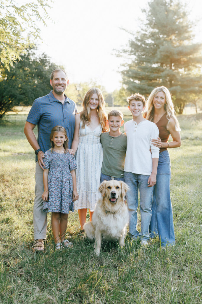 family in a field with kids and dog posing for photo