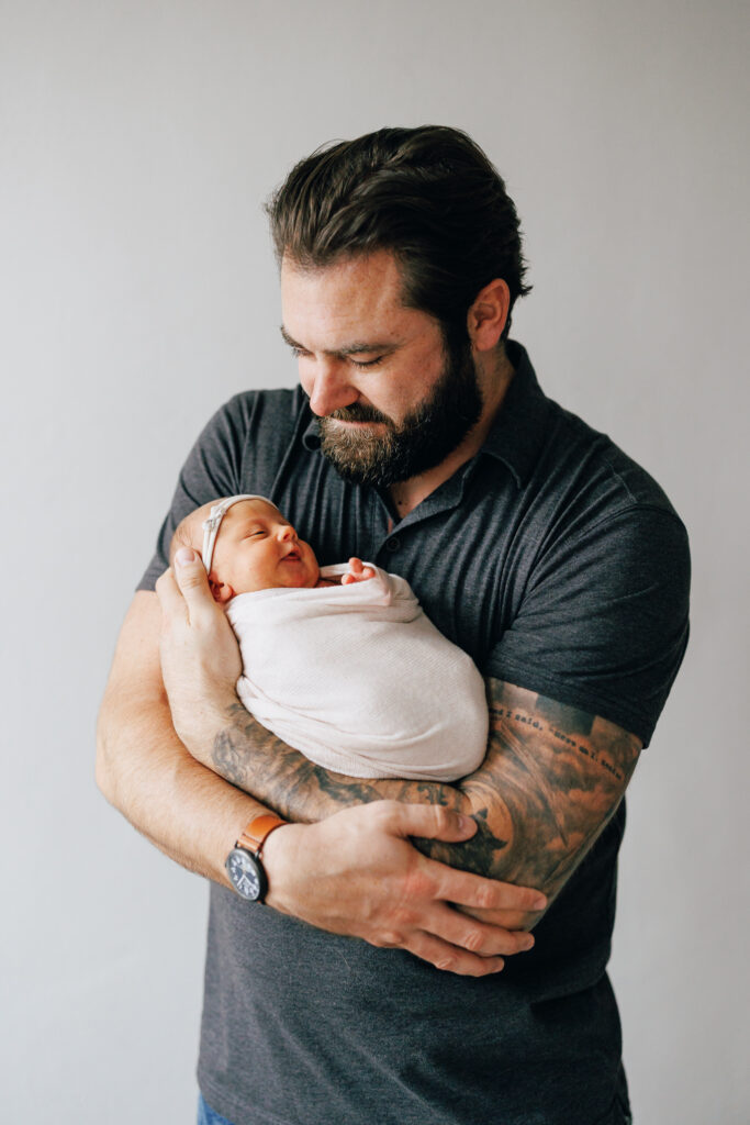 big guy new dad holding baby newborn daughter who looks so small in his arms